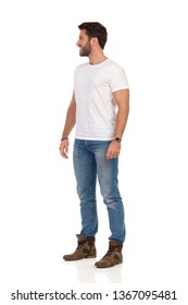 Smiling Man In Jeans And White T-shirt Is Standing And Looking Away. Side View. Full Length Studio Shot Isolated On White.