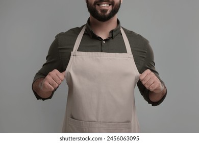 Smiling man in kitchen apron on grey background, closeup. Mockup for design