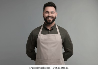 Smiling man in kitchen apron on grey background. Mockup for design