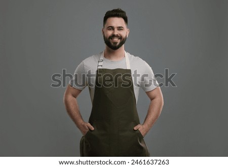 Smiling man in kitchen apron on grey background. Mockup for design