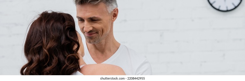 Smiling Man Looking At Brunette Wife In Kitchen, Banner