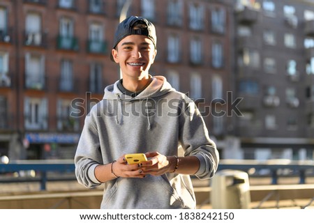 smiling man looking at the camera with his phone in his hand in the street