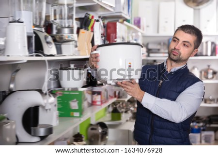Smiling man is looking on multivariates for kitchen in store