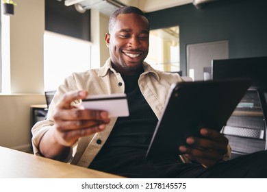 Smiling Man Making Online Payment On Tablet Computer Holding Credit Card