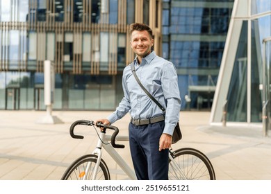 A smiling man with a messenger bag poses next to his bicycle in front of a contemporary glass building. - Powered by Shutterstock