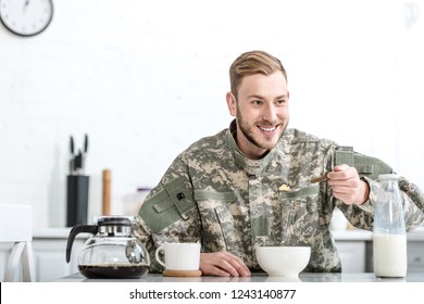 Smiling Man In Military Uniform Eating Cornflakes At Kitchen