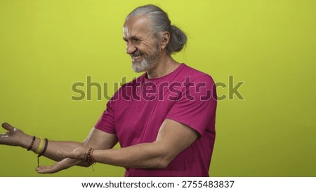 Smiling man with open hands presenting palm up in studio with lime green backdrop; welcoming sincerity.