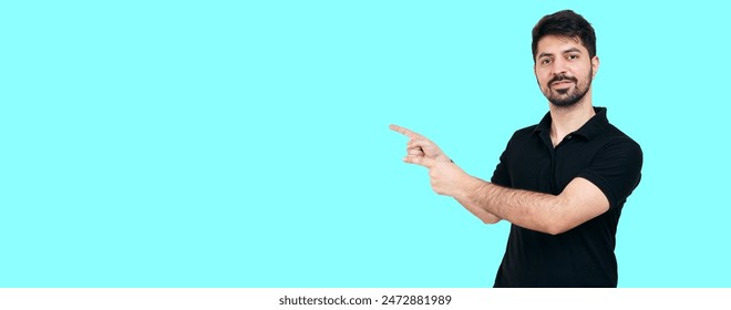 Smiling Man Pointing to Copy Space on Blue Background. Advertisement and Marketing Concept with Young Male in Casual Attire Highlighting Important Information or Product. Boy pointing. Boy gesture - Powered by Shutterstock