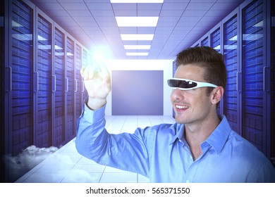 Smiling man pointing while using virtual video glasses against server room with towers