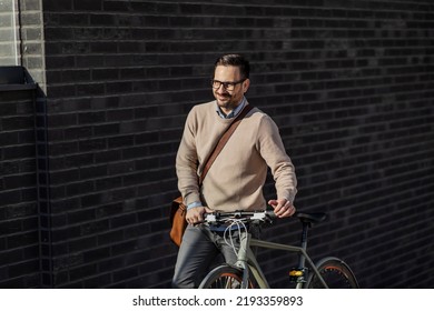 A Smiling Man Pushing A Bicycle Uphill On The City Street.