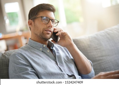 Smiling man relaxing in sofa, talking on phone - Shutterstock ID 1524247409