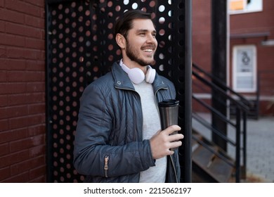 Smiling Man With Reusable Metal Coffee Cup And Earphones And Looks Into The Distance