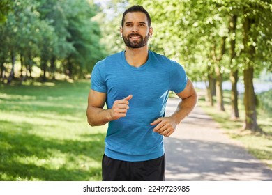 Smiling man running in park at sunny summer day - Powered by Shutterstock