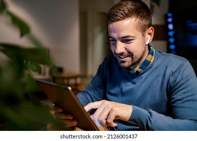 A Smiling Man Scrolling On The Tablet And Searching Internet While Sitting At Home.