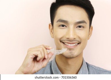 Smiling Man With Silicone Trainer Close Up For More Whitening Teeth, Hand Holding Invisible Braces For Home Whitening Or Bleaching Gel Tray Opalescence.