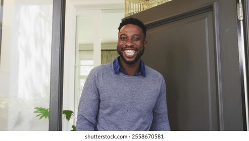 Smiling man standing at front door, welcoming guests into cozy home. Hospitality, warmth, entrance, friendship, cheerful, invitation - Powered by Shutterstock