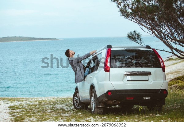 smiling man stick out from\
car window. summer sea on background. copy space. rent car travel\
concept