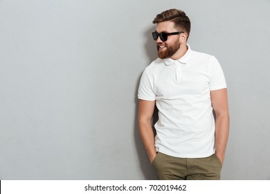 Smiling Man In Sunglasses Posing In Studio And Looking Away Over Gray Background