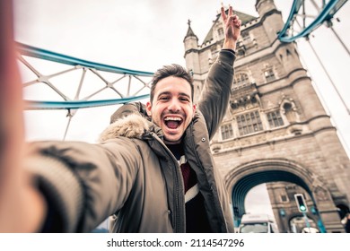 Smiling man taking selfie portrait during travel in London, England - Young tourist male taking holiday pic with iconic england landmark - Happy people wandering around Europe concept