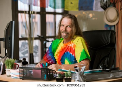 Smiling Man In Tie Dye Shirt At His Desk