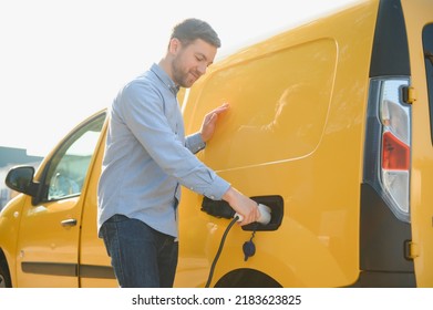 Smiling man unplugging the charger from the car. - Shutterstock ID 2183623825