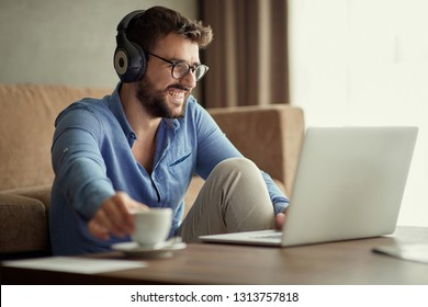 Smiling man uses a laptop to listen to music and relax at home