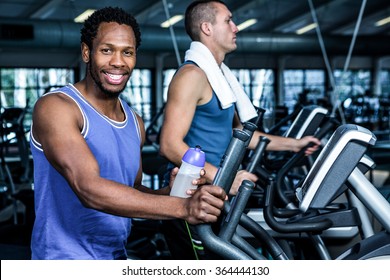 Smiling Man Using Elliptical Machine At Gym