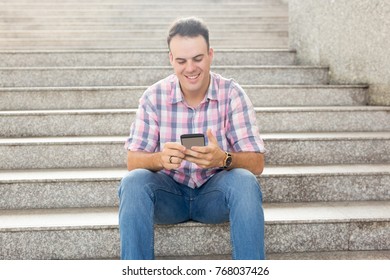 Smiling Man Using Smartphone on City Stairway