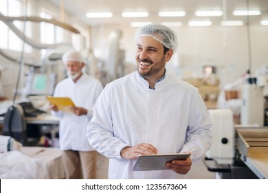 Smiling Man Using Tablet While Standing In Food Factory.