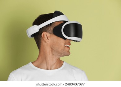 Smiling man using virtual reality headset on light green background - Powered by Shutterstock