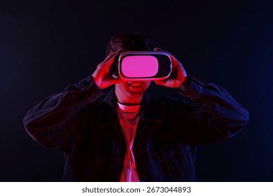 Smiling man using virtual reality headset in neon lights against black background