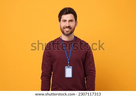 Smiling man with VIP pass badge on orange background