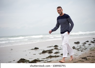 Smiling Man Walking Barefoot On A Sandy Beach.