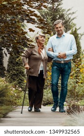 Smiling Man Walking With Happy Elderly Woman In The Garden