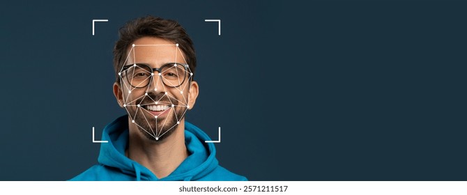 A smiling man wears glasses and a hoodie while facial recognition technology overlays a geometric pattern on his face. The background is a solid color, emphasizing facial identification.
