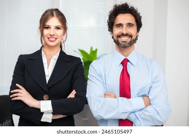 Smiling man and woman in business attire standing confidently in an office environment - Powered by Shutterstock