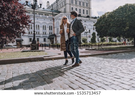 Smiling man and woman with coffee outdoors 