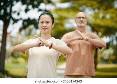 Smiling man and woman doing fist palm salute when practicing tai chi - Powered by Shutterstock