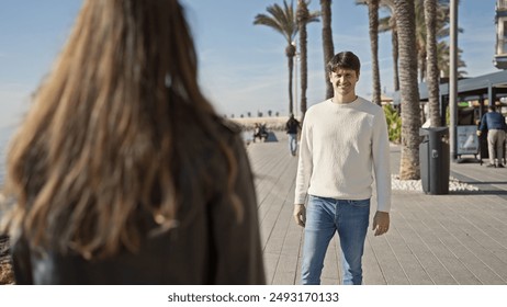 A smiling man and woman enjoying a sunny day together at a palm-lined beach promenade. - Powered by Shutterstock