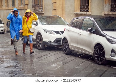 Smiling Man And Woman In Raincoats Are Running In The Rain