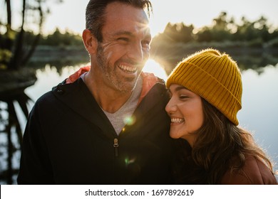 Smiling man and woman standing together by the lake. Cheerful couple together on a camping trip. - Powered by Shutterstock