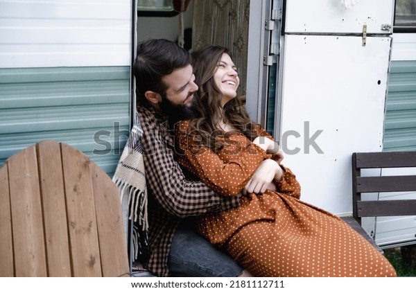 Smiling man and woman traveling in travel van.\
Romantic atmosphere of relaxation. Road trip around country for the\
weekend. Happy caucasian loving couple embracing in trailer.\
Millennial generation