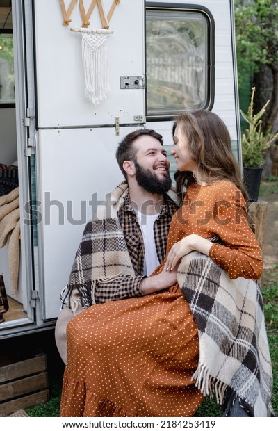 Smiling man and woman traveling in travel van.
Romantic atmosphere of relaxation. Road trip around country for the
weekend. Happy caucasian loving couple embracing at trailer.
Millennial generation