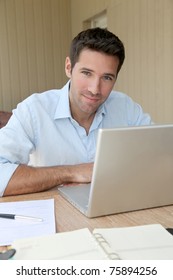 Smiling Man Working At Home On Laptop Computer