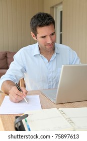 Smiling Man Working At Home On Laptop Computer