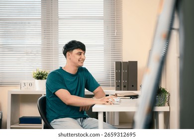 Smiling man working on computer at desk in a modern home office with natural light