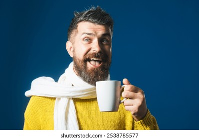 Smiling man in yellow sweater and white scarf drinking coffee or tea from mug. Handsome male in casual wear holds cup with hot beverage. Coffee break. Bearded man with mug of fragrant coffee or tea - Powered by Shutterstock