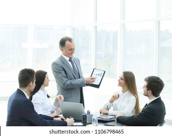 smiling Manager showing a business team ,a graph with financial data.
