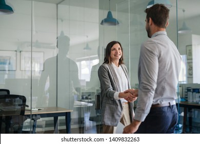 Smiling manager standing outside of her office shaking hands with a new employee after an interview