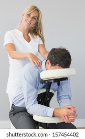 Smiling Masseuse Treating Clients Neck In Massage Chair In Bright Room